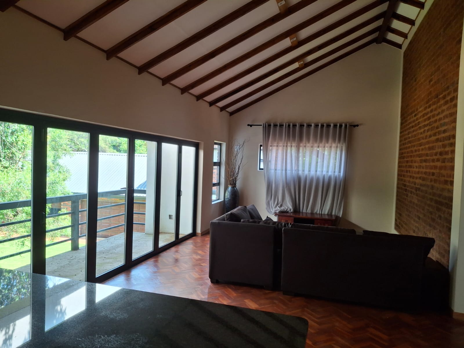 Inside one of the units &middot; vaulted timber-beam ceiling, brick accent wall, sliding doors onto a private balcony