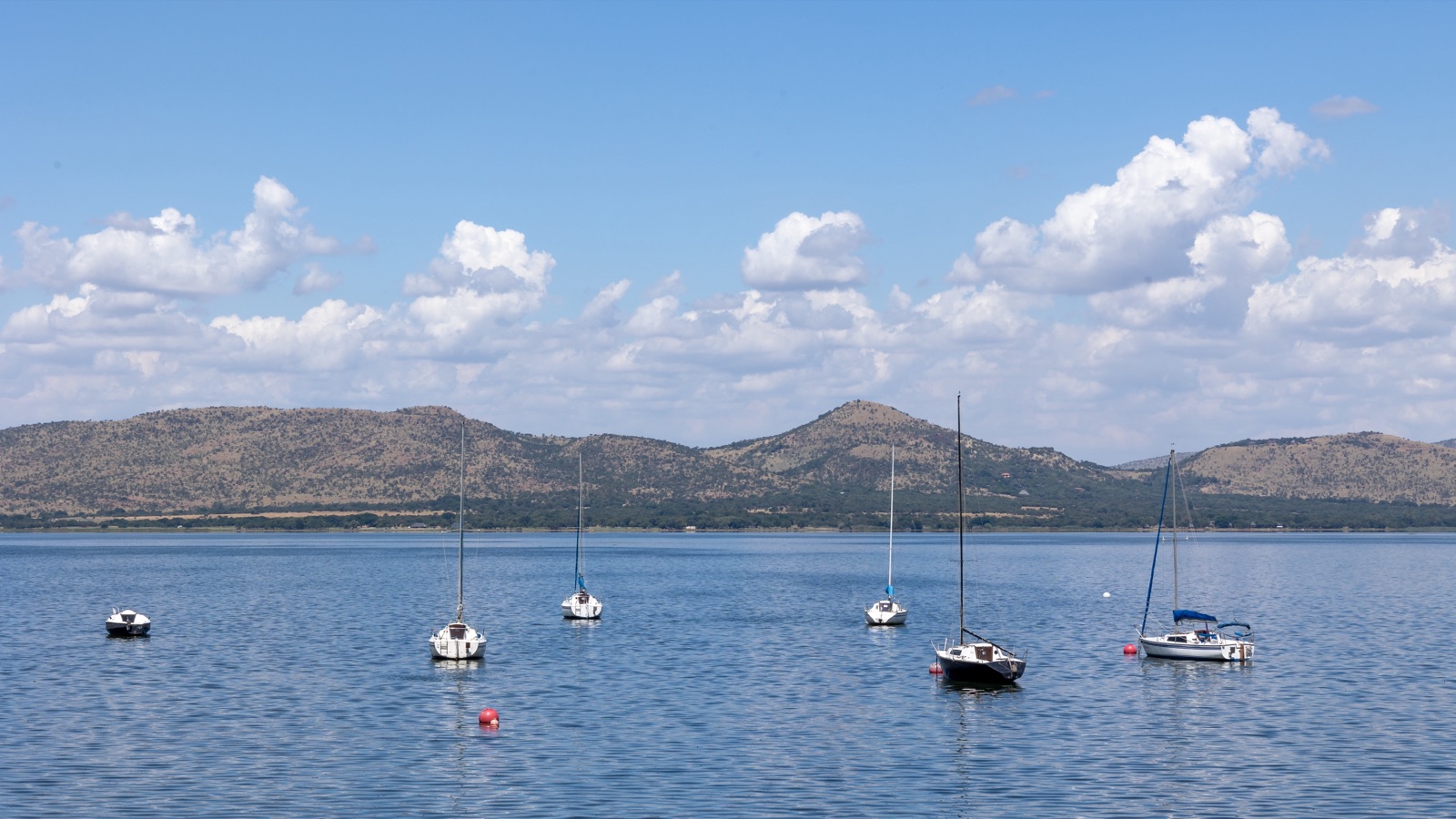 Sailboats on a dam with mountain backdrop